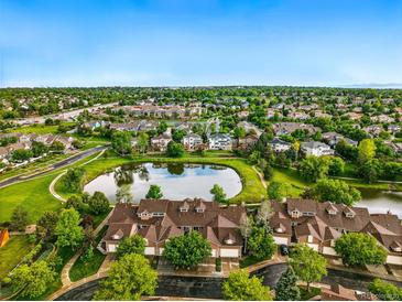 Stunning aerial view of townhomes surrounding a tranquil pond, with lush greenery and a clear blue sky at 3240 W 114Th Cir # D, Westminster, CO 80031