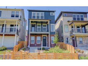 Charming exterior of a three-story home with a blue facade, brick accents, and a fenced front yard at 11063 Shining Star Cir, Parker, CO 80134