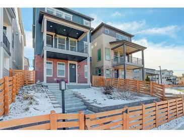 Beautiful two-story home boasts a brick facade, dual balconies, fenced yard, and wintery curb appeal at 11063 Shining Star Cir, Parker, CO 80134