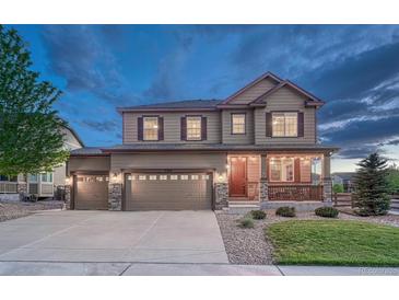 Charming two-story home featuring a three-car garage, stone accents, and a cozy covered front porch at 7310 Blue Water Dr, Castle Rock, CO 80108