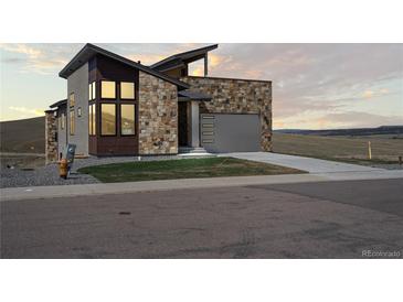 Modern home featuring stone accents, a gray garage door, and professionally landscaped front yard at 5741 Doc Bar Circle, Larkspur, CO 80118