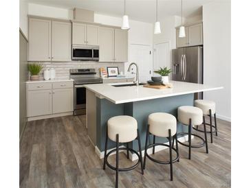 Modern kitchen with stainless steel appliances, a center island, and bar stool seating at 6153 N Ceylon St # 102, Denver, CO 80249