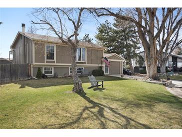 Charming two-story home featuring a well-maintained lawn, mature trees, and a cozy seating area at 9590 W Eureka Pl, Lakewood, CO 80227
