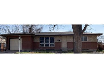 Charming single-story home featuring a brick and stone facade, a lamp post, and an attached garage at 426 Kenton St, Aurora, CO 80010
