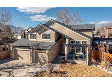 Inviting two-story home with a well-manicured lawn, a two-car garage, and a charming front porch at 14023 W Amherst Pl, Lakewood, CO 80228