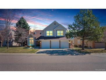 Charming two-story home features a 3-car garage, lush lawn, and well-maintained landscaping under a beautiful evening sky at 7340 Brixham Cir, Castle Pines, CO 80108