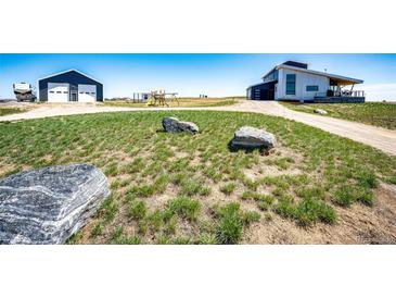 Modern home exterior featuring a spacious yard, garage, and additional storage building at 43010 Ptarmigan Ranch St, Parker, CO 80138