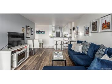 Cozy living room featuring a plush blue sectional sofa, a glass coffee table, and a view into the bright white kitchen at 800 N Washington St # 804, Denver, CO 80203
