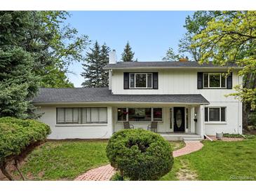 Inviting two-story home showcasing a manicured lawn and brick pathway leading to the covered front porch at 11880 W 30Th Pl, Lakewood, CO 80215