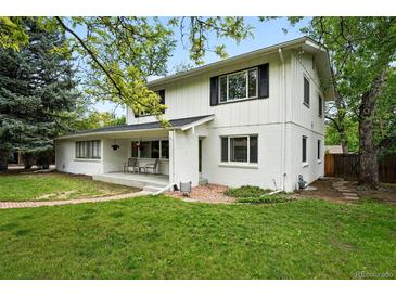 Charming two-story home featuring a brick-and-wood facade and a welcoming front porch, surrounded by lush greenery at 11880 W 30Th Pl, Lakewood, CO 80215