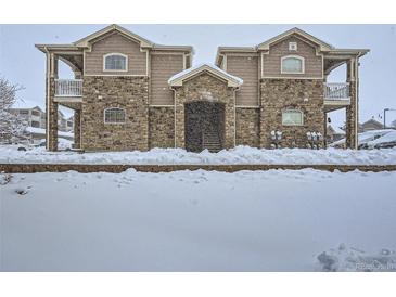 Condominium exterior with stone facade and snow-covered grounds, creating a cozy winter scene at 7440 S Blackhawk St # 9-108, Englewood, CO 80112