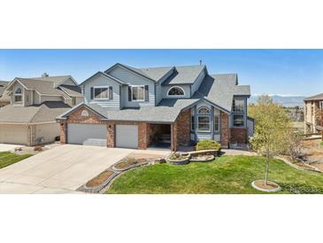 Charming two-story home featuring a manicured lawn, brick accents, and a spacious three-car garage at 9895 Wyecliff Dr, Highlands Ranch, CO 80126