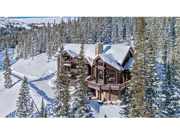 Stunning log cabin home surrounded by snow-covered trees, featuring a stone foundation and inviting balconies at 351 Kimmes Ln, Breckenridge, CO 80424