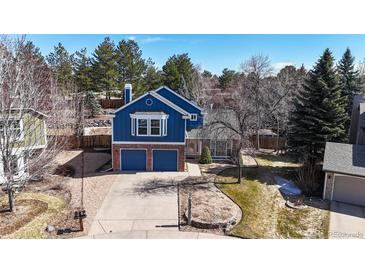 Beautiful two-story home featuring a brick and blue-sided facade, two-car garage, and mature landscaping at 7464 Shoreham Pl, Castle Pines, CO 80108