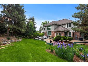 Expansive backyard featuring a large lawn, mature trees, patio with seating, and beautiful landscaping at 6132 S Boston Cir, Greenwood Village, CO 80111