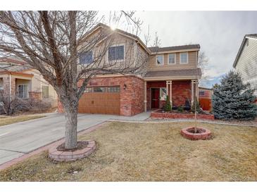 Inviting two-story home with a brick facade, a manicured lawn, and an American flag at 11701 Elkhart St, Commerce City, CO 80603