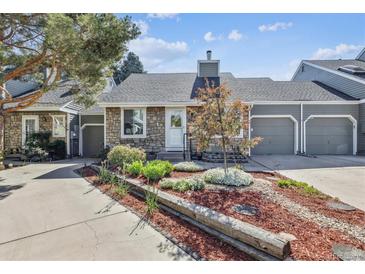 Charming home featuring stone and gray wood siding, a landscaped yard, and an attached two-car garage at 4720 S Dudley St # 38, Littleton, CO 80123