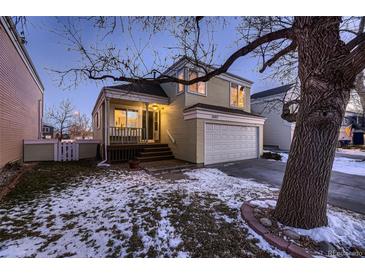 Evening view of charming two-story home with attached garage and snowy front yard at 2697 S Deframe Cir, Lakewood, CO 80228