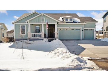 Two-story house with a light green exterior, two-car garage, and a snowy front yard at 1030 W Hopkins Dr, Elizabeth, CO 80107