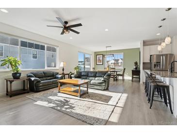 Bright, open-concept living room featuring hardwood floors, modern ceiling fan and ample natural light at 1030 W Hopkins Dr, Elizabeth, CO 80107