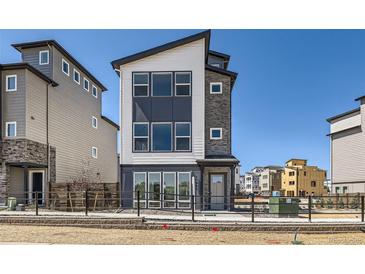 Modern three-story home with a sleek design, large windows, and a well-maintained front yard at 10863 E Hinsdale Cir, Centennial, CO 80112