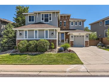 Charming two-story home featuring stone accents, lush landscaping, and a two car garage on a sunny day at 11074 Grayledge Cir, Highlands Ranch, CO 80130