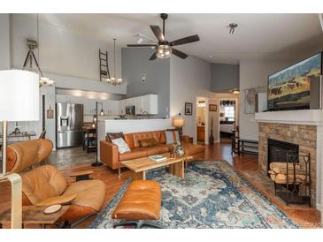Inviting living room featuring a cozy leather couch, fireplace, and a stylish ceiling fan at 3242 E 103Rd Dr # 602, Thornton, CO 80229