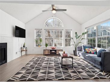 Bright living room with vaulted ceilings, large windows, and a modern patterned rug at 6755 S Ivy St # A7, Centennial, CO 80112