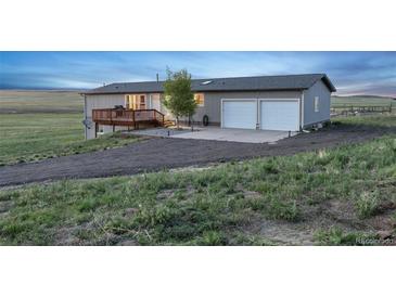 Single story gray house with a wood deck, two-car garage, and lawn at 11100 Haskell Creek Rd, Larkspur, CO 80118