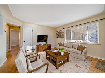 Cozy living room with hardwood floors, area rug, and comfortable seating by a large window at 4157 Perry St, Denver, CO 80212