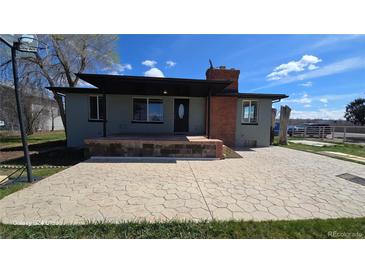 Charming single-story home featuring a spacious front patio, brick chimney, and well-maintained landscaping at 15600 E 33Rd Pl, Aurora, CO 80011
