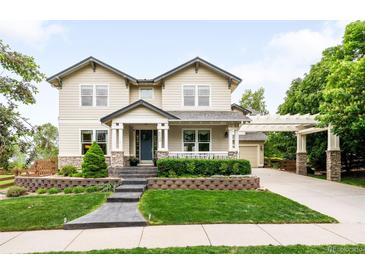 Charming two-story home featuring a well-manicured front yard, inviting entrance, and an attached garage with a pergola-covered driveway at 6032 Umber St, Arvada, CO 80403