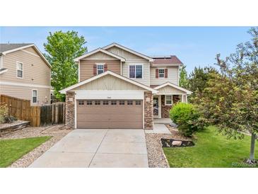 Two-story home featuring a neutral color palette, complemented by a stone-accented garage and a well-manicured front lawn at 13664 Linden Ct, Thornton, CO 80602