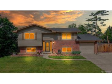 Charming split-level home showcasing a well-maintained lawn, brick accents, and a welcoming entrance at 6631 Welch Ct, Arvada, CO 80004