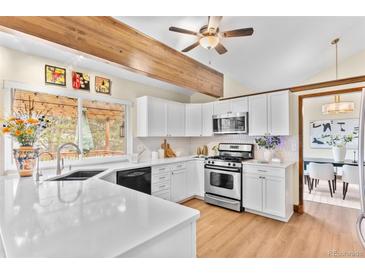 Bright kitchen features white cabinets, stainless steel appliances, and a window offering view of the backyard at 11545 Quivas Way, Westminster, CO 80234