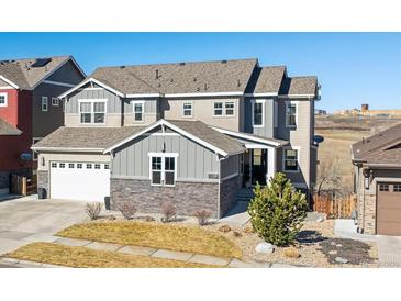 Beautiful two-story home featuring gray siding, stone accents, a well-manicured lawn and an attached two car garage at 17577 W 87Th Ave, Arvada, CO 80007