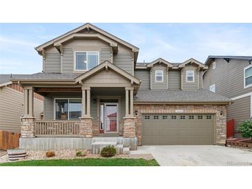 Charming two-story home featuring a covered porch with stone accents and a two-car garage at 16685 E 101St Ave, Commerce City, CO 80022