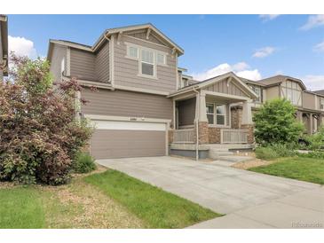 Charming two-story home with a two-car garage, inviting front porch with stone accents and beautifully landscaped front yard at 6484 N Ceylon Ct, Denver, CO 80249