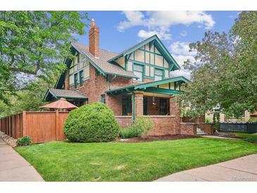 Charming two-story home featuring a brick facade, green trim, a well-manicured lawn, and mature trees at 2201 Cherry St, Denver, CO 80207