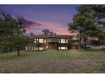 Stunning two-story home with beautiful architecture surrounded by lush landscaping and a colorful sky at 22453 Hillcrest Cir, Golden, CO 80401