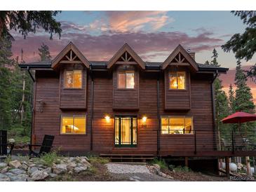 Inviting craftsman-style home featuring a warm wood facade, multiple gables, and outdoor living space at dusk at 592 Brook Dr, Idaho Springs, CO 80452