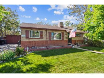 Charming brick home featuring a well-maintained lawn, beautiful garden, and an American flag at 9301 Ciancio St, Thornton, CO 80229