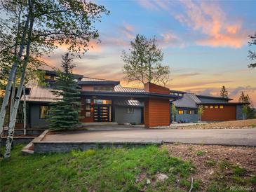 Stunning home exterior featuring modern architecture, natural wood accents, and mountain views at sunset at 34089 Woodland Dr, Evergreen, CO 80439