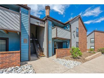 Charming condo exterior with blue siding, brick accents, and well-maintained landscaping under a bright sky at 12037 E Harvard Ave # 104, Aurora, CO 80014