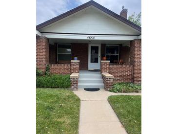 Charming brick home featuring a covered front porch and well-maintained lawn and walkway at 4654 Bryant St, Denver, CO 80211