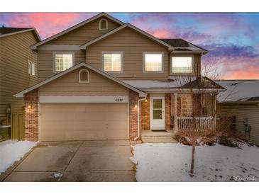 Charming two-story home with a two-car garage and a cozy front porch, surrounded by a snow-covered yard at 4821 N Silverlace Dr, Castle Rock, CO 80109