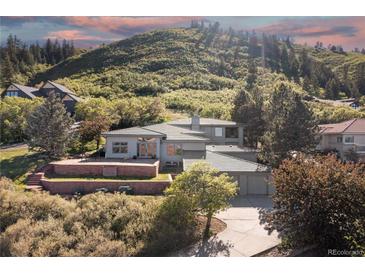 Stunning exterior elevation of home situated on a terraced lot with mountain views and mature trees at 11039 Roxborough Dr, Littleton, CO 80125