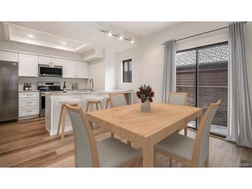 Bright dining room featuring wood table and chairs with access to modern kitchen at 2685 S Dayton Way # 234, Denver, CO 80231