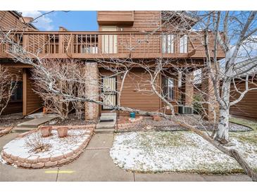 Charming townhome showcasing a private entrance with a cozy balcony, complemented by a partially snow-covered front yard at 2685 S Dayton Way # 234, Denver, CO 80231