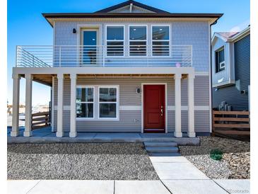 Charming two-story home with a red front door, gray siding and a balcony, creating curb appeal at 46554 Avery Ln, Bennett, CO 80022